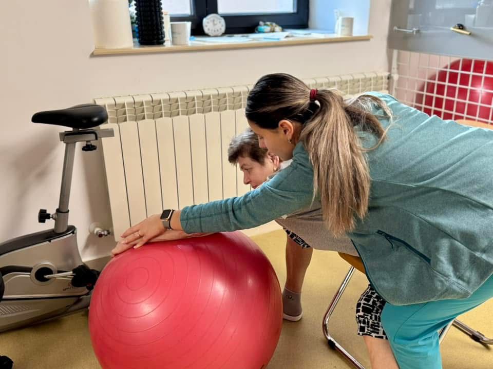 Pacientă în vârstă face exerciții de recuperare sub supravegherea kinetoterapeutei la clinica TrifMed din Fălticeni.