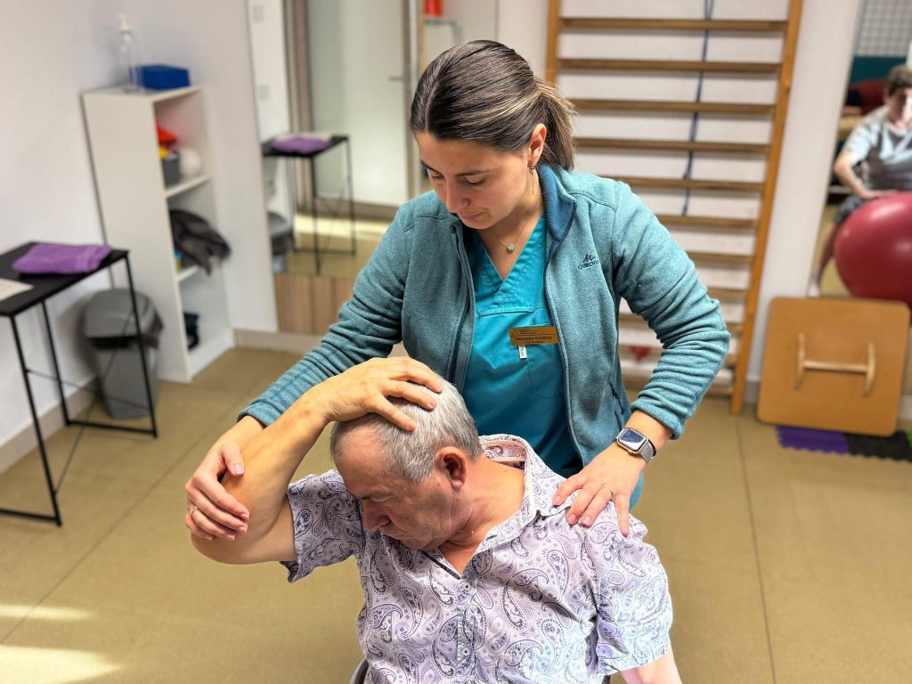 Fizioterapeută asistă un pacient senior la exerciții de recuperare medicală în cadrul clinicii din Fălticeni.